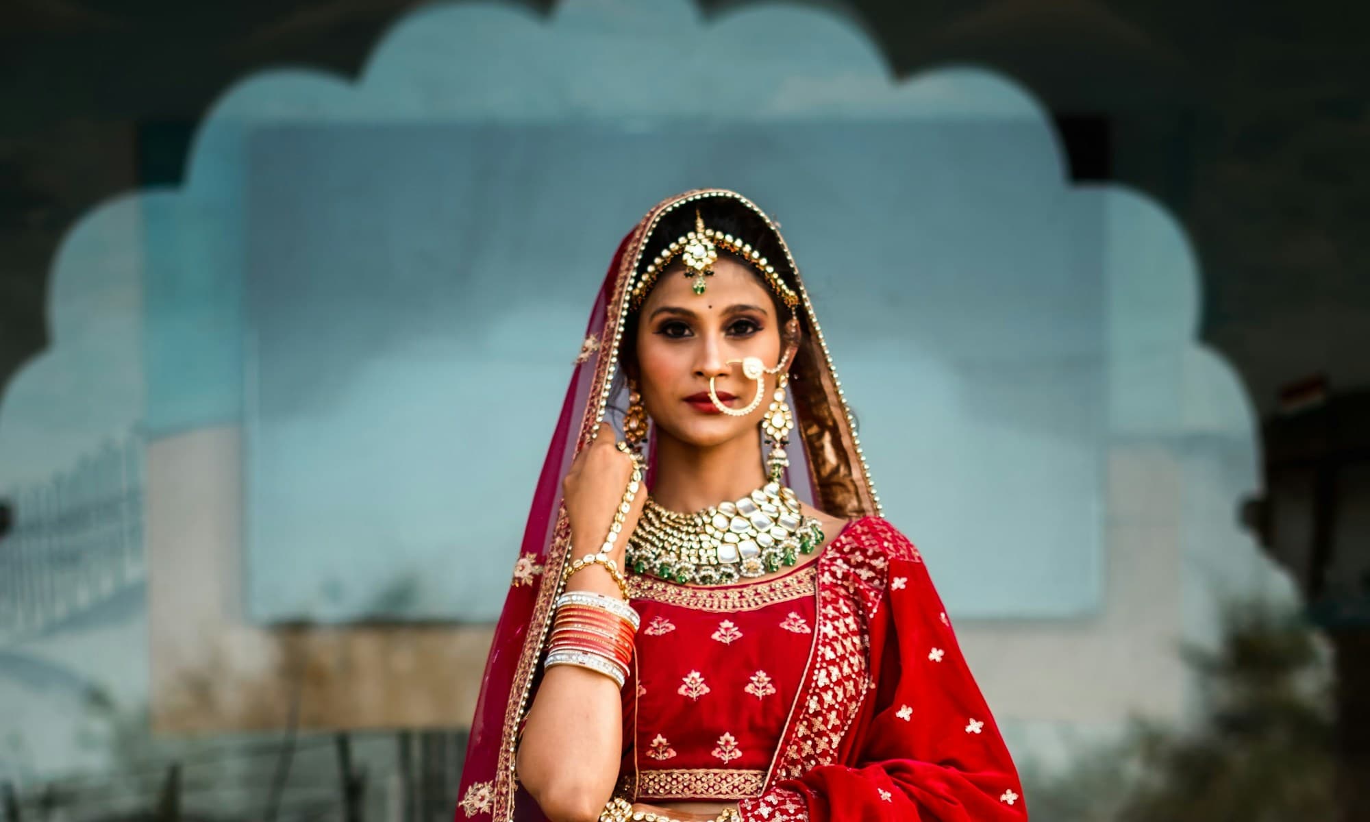 Bride in a red and gold bridal lehenga with traditional jewellery