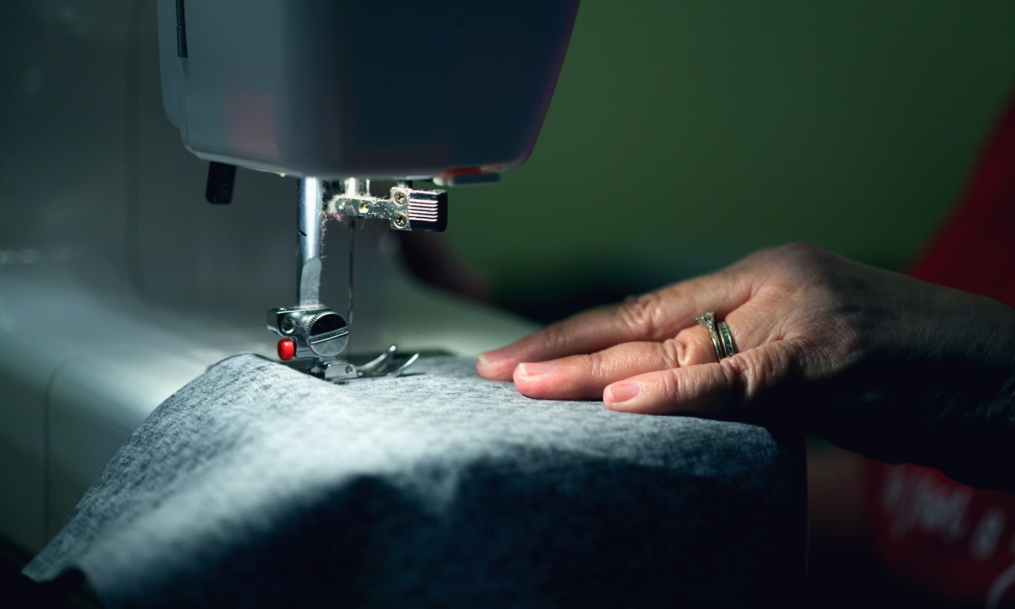Tailor at a sewing machine, working fabric through by hand