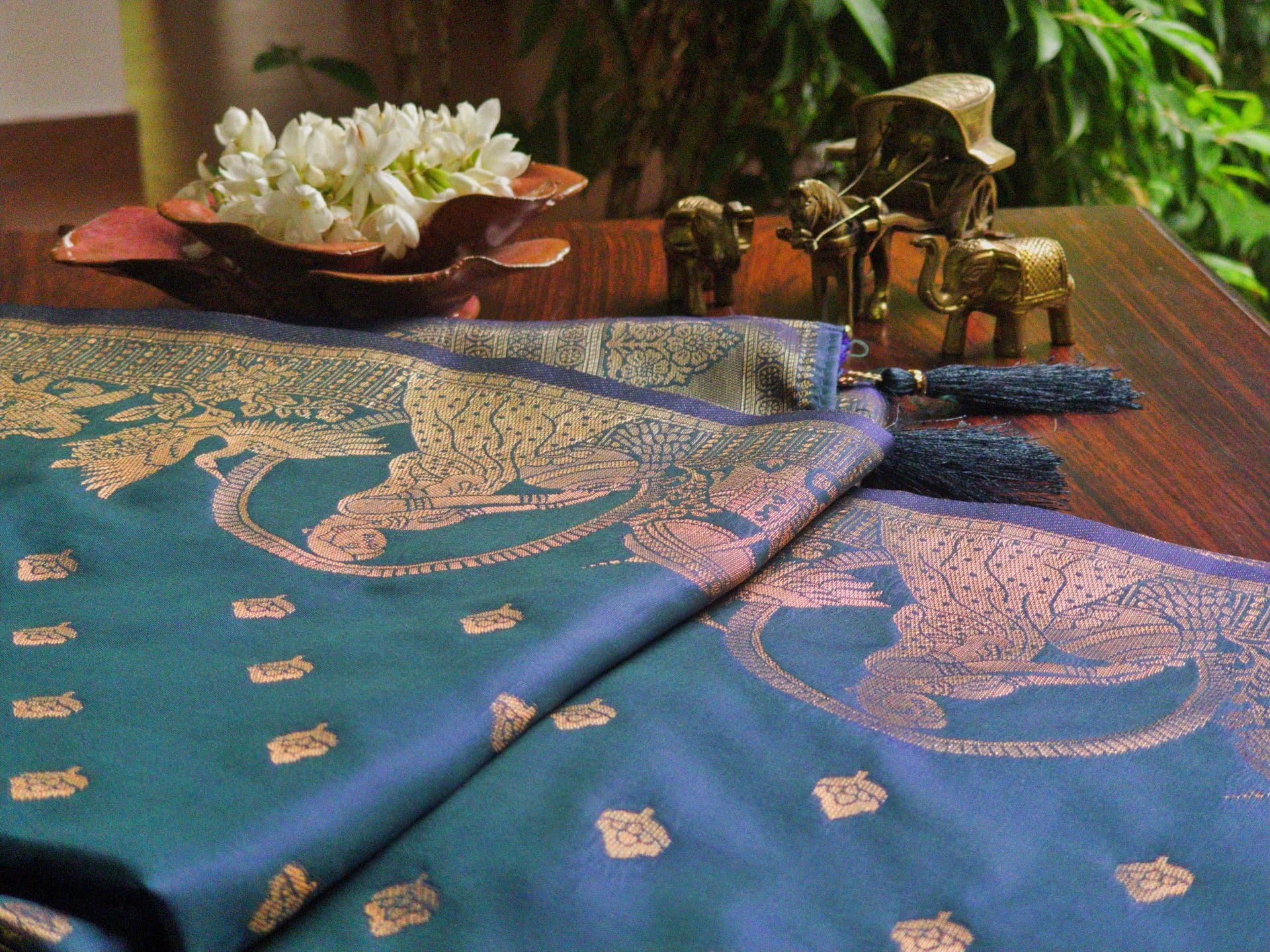 Blue Banarasi silk sari woven with gold motifs, laid out with jasmine and brass
